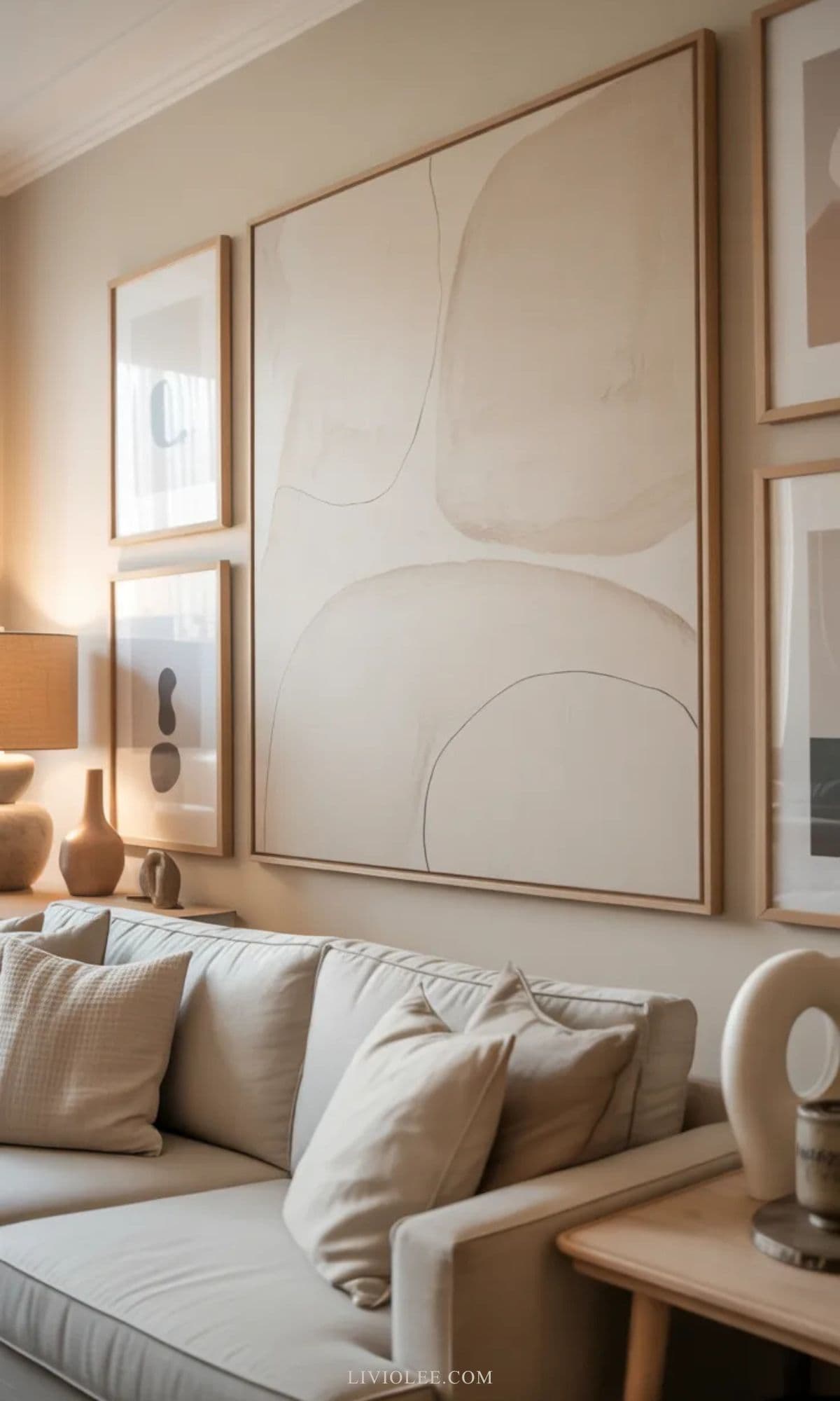 Neutral living room wall with minimalist beige artwork, wood frames, linen sofa, and simple decorative accents