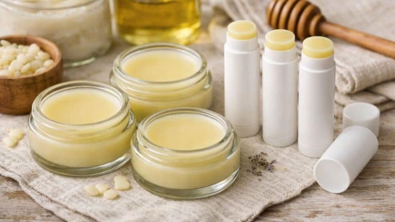 Homemade tallow lip balm in small glass jars and white tubes on a linen cloth with natural ingredients like beeswax and oil