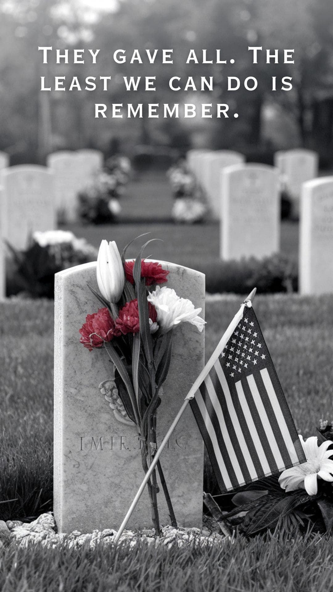 Black-and-white Memorial Day image featuring a military gravestone adorned with red and white flowers and a small American flag