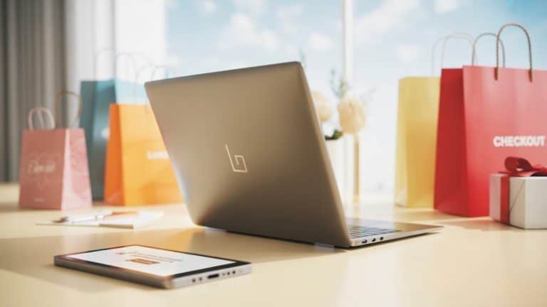 laptop computer surround by online shopping retail bags